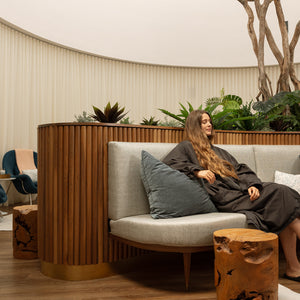 Woman sitting on a gray sofa with decorative pillows in a modern interior setting.