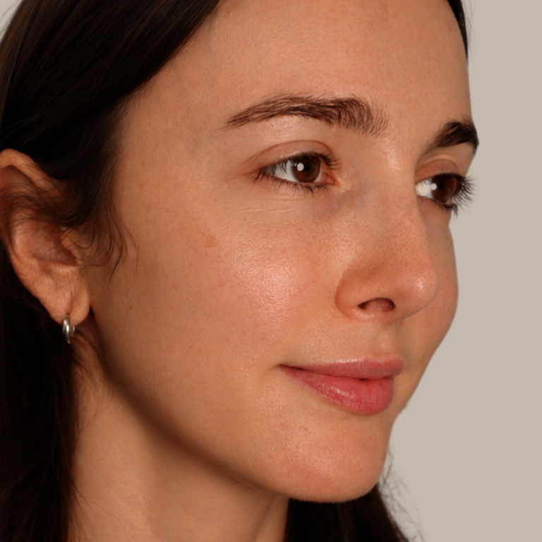 A close-up portrait of a woman wearing a small silver hoop earring, shown from the side against a plain light gray background.