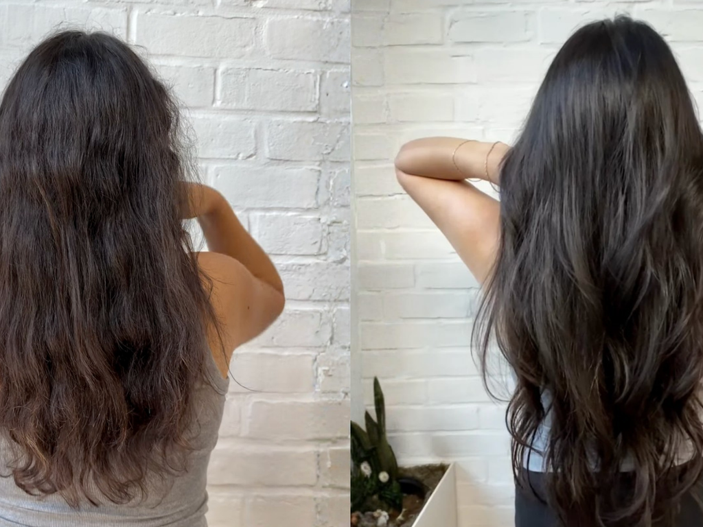 A side-by-side comparison of a woman's long, dark brown hair, showing frizzy, textured hair on the left and smooth, shiny, wavy hair on the right, set against a white brick wall background.