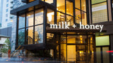 Modern building with 'milk + honey' sign on a city street