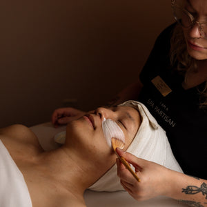 Person receiving a facial treatment with a professional in a spa setting.