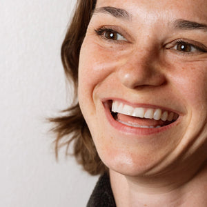 Close-up of a person smiling with a neutral background
