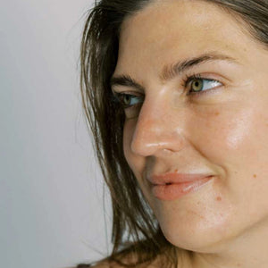 Close-up of a woman's face with a neutral expression on a plain background