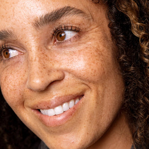 Close-up of a woman with a warm smile and brown eyes.