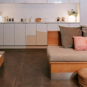 Modern living room with a wooden bench and cushions against a white wall.