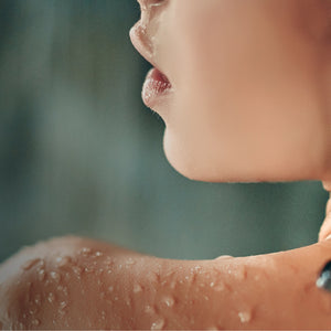 Close-up of a person's shoulder and neck with water droplets, blurred background