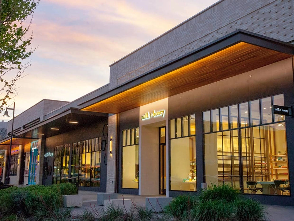 Modern building exterior with glass windows and a sunset sky.