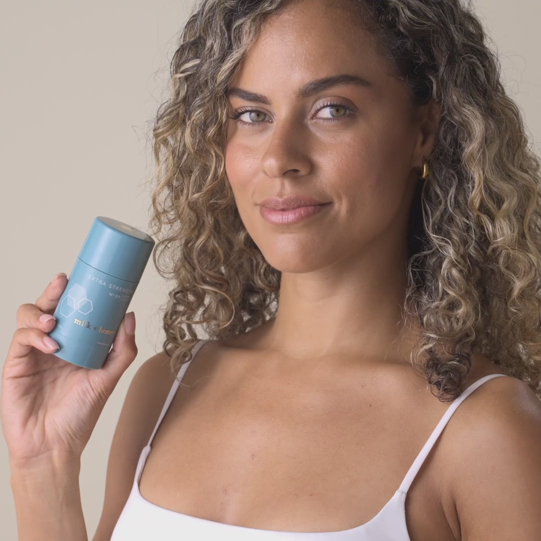 Woman smiling while holding milk+honey Number 9 product.