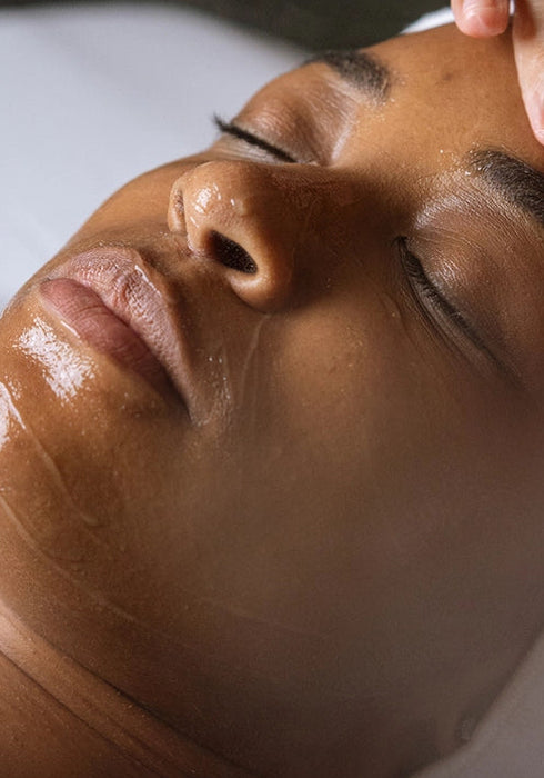 Person receiving a facial treatment with a hand applying product to the face.